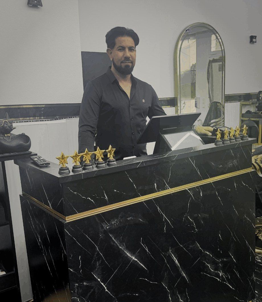 Reza, Inhaber und Barber, am Empfangstresen mit fünf goldenen Sternen